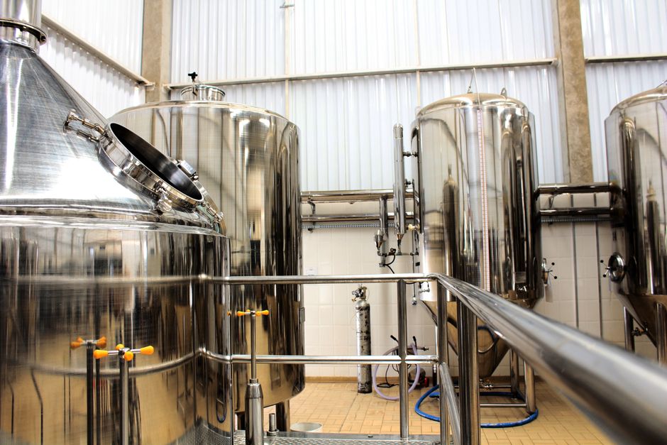 A view of stainless steel tanks in a modern brewery, showcasing industrial machinery and production equipment. (Photo: Daniel Dan / Pexels)