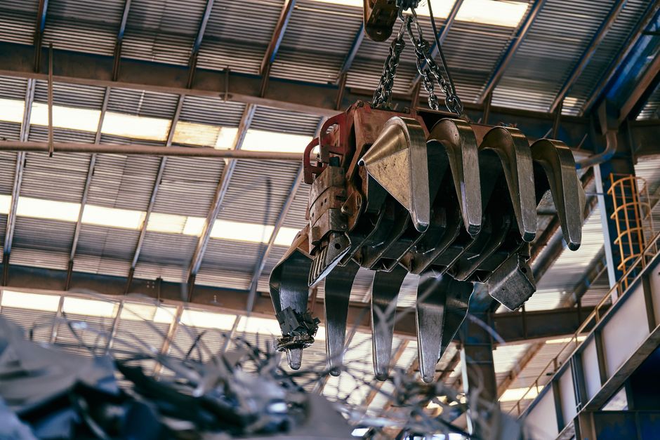 Large industrial crane handling scrap metal in a warehouse setting. (Photo: Willians Huerta / Pexels)