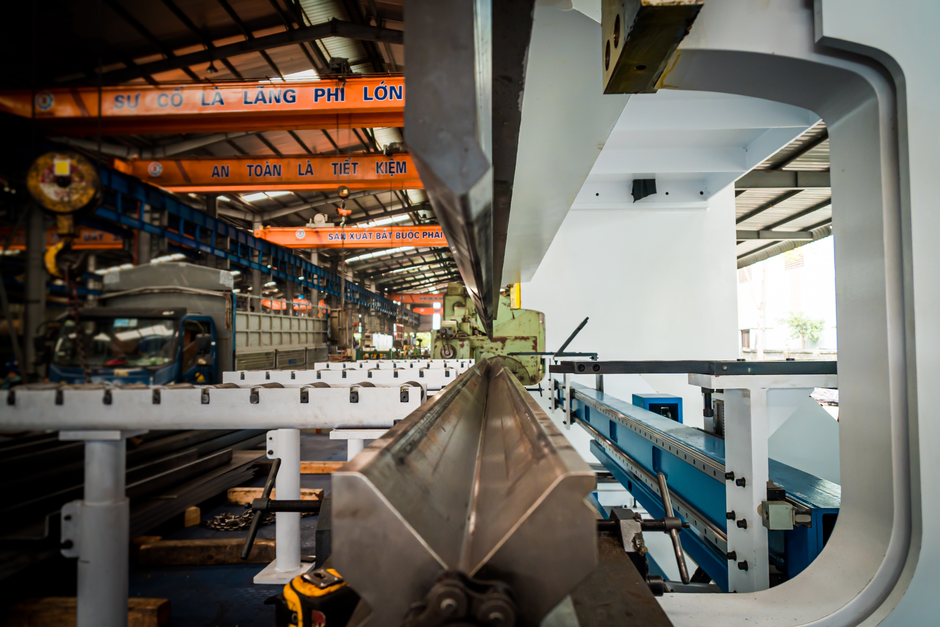 Interior view of an industrial building featuring machinery and metal conveyor systems. (Photo: Hoang NC / Pexels)