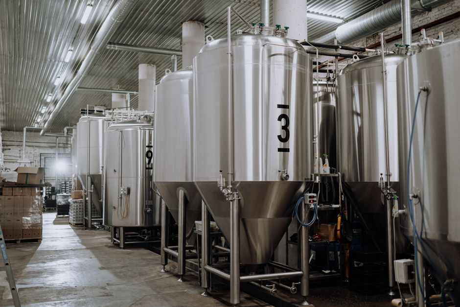 Interior view of a modern brewery showcasing stainless steel fermentation tanks. (Photo: cottonbro studio / Pexels)