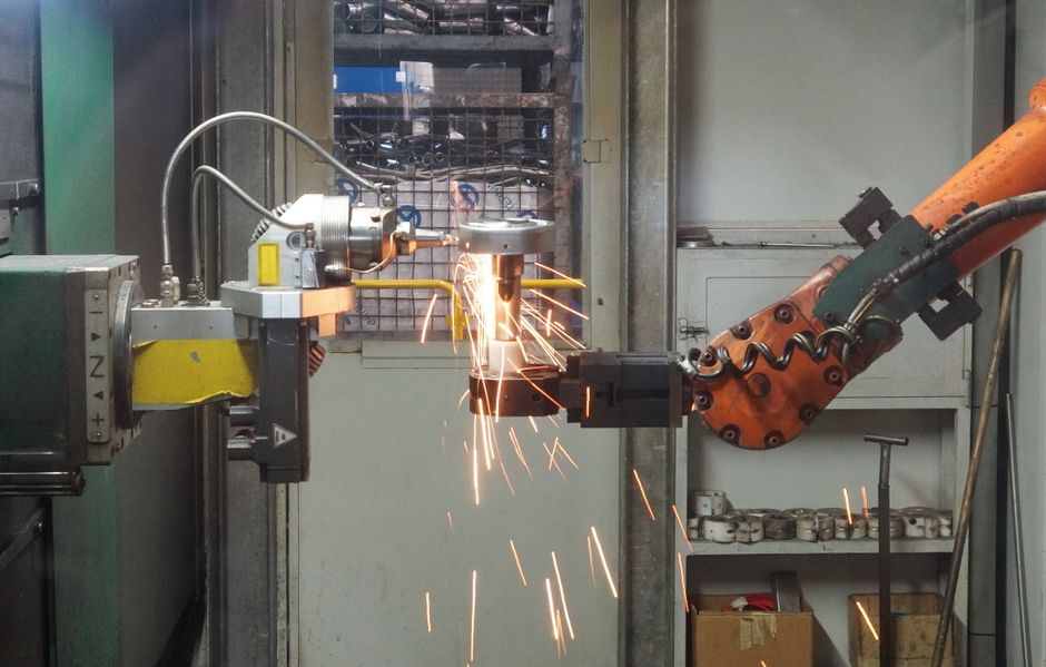 A robotic arm welding in an industrial setting, emitting bright sparks. (Photo: alex / Pexels)