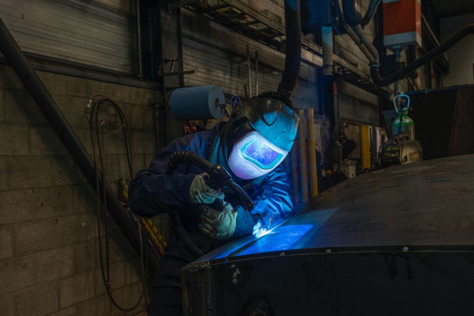 Welder wearing protective gear working in industrial workshop environment. (Photo: Rik Schots / Pexels)