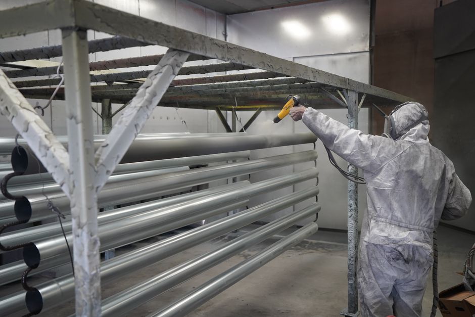 Technician applying powder coating to metal pipes in a workshop setting. (Photo: Full Blown Coatings https://www.fullblowncoatings.com/ / Pexels)