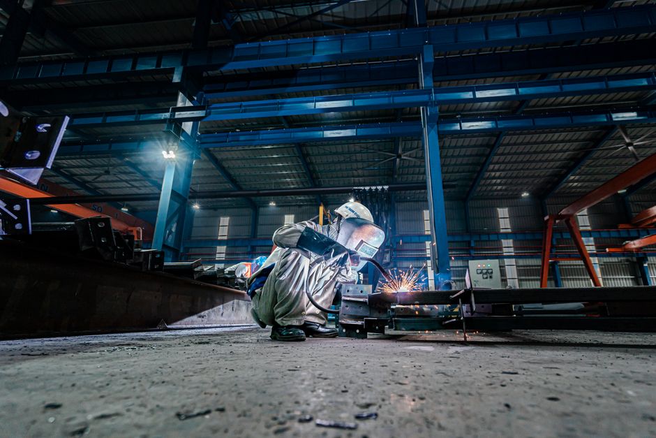 Skilled welder working on steel structures with bright sparks flying indoors. (Photo: Hoang NC / Pexels)
