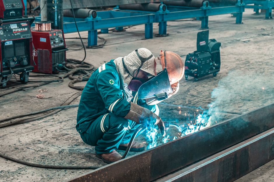 A welder using protective gear works on metal in a factory workshop. (Photo: Hoang NC / Pexels)