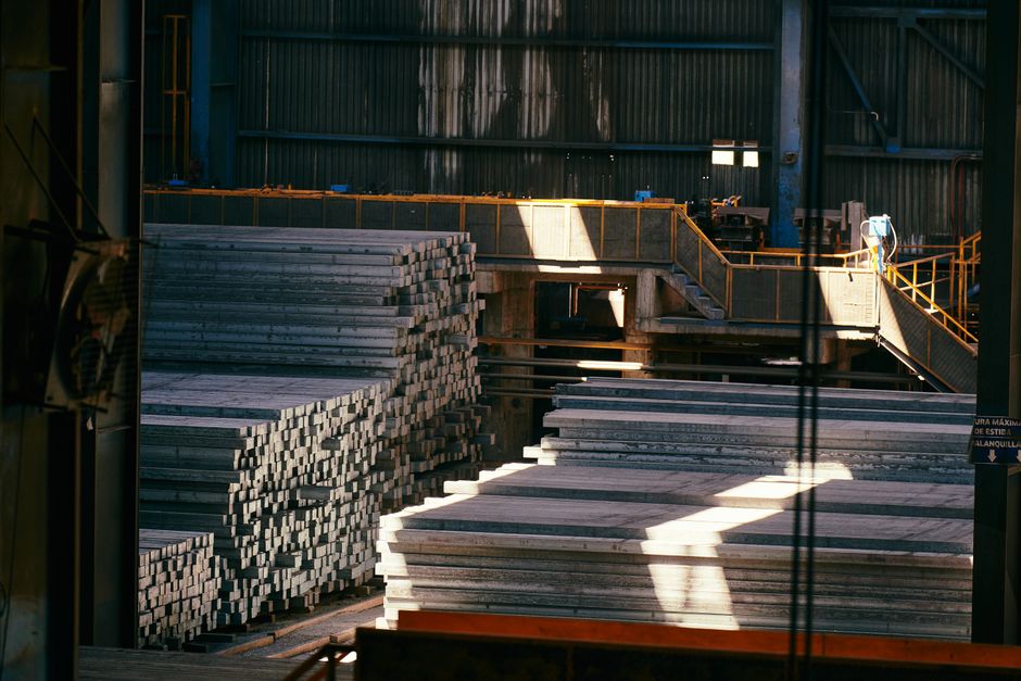 Interior view of a large industrial warehouse with stacked metal sheets and beams. (Photo: Willians Huerta / Pexels)