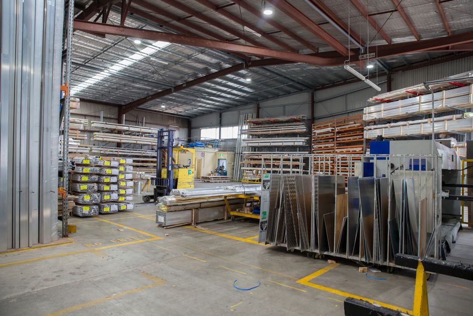 Wide view of an industrial warehouse interior showcasing stacks of steel and metal sheets. (Photo: James Richardson / Pexels)