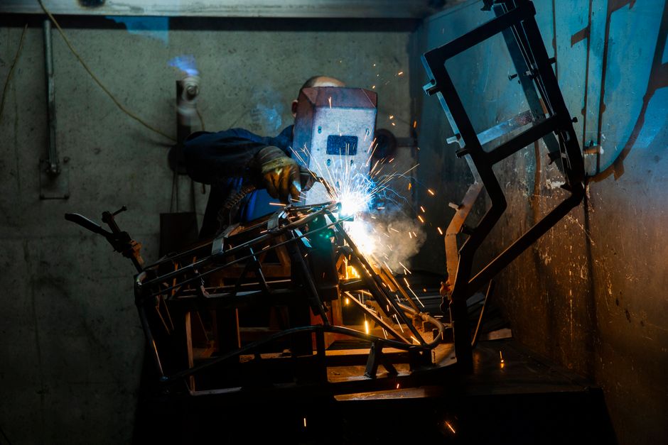 A welder working with sparks and smoke indoors, showcasing industrial skill and safety. (Photo: Engin Akyurt / Pexels)