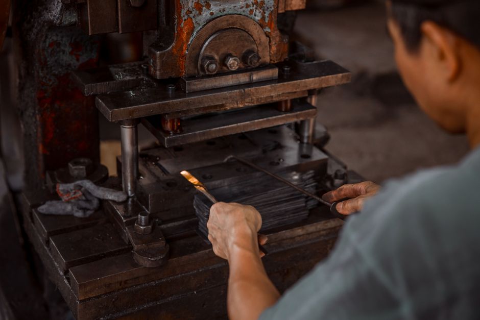 Close-up of worker using industrial press in metalworking process. (Photo: HONG SON / Pexels)