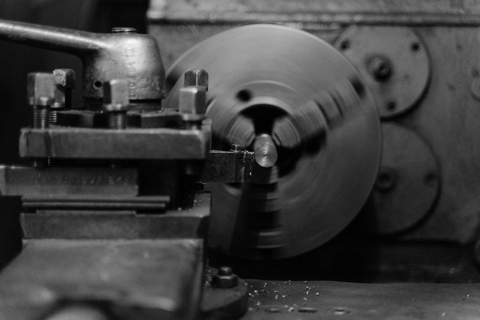 Black and white close-up of an industrial lathe machine showing its intricate mechanical details. (Photo: Tima Miroshnichenko / Pexels)