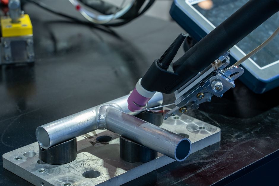Detailed view of metal welding apparatus in action on industrial workbench. (Photo: Peter Xie / Pexels)