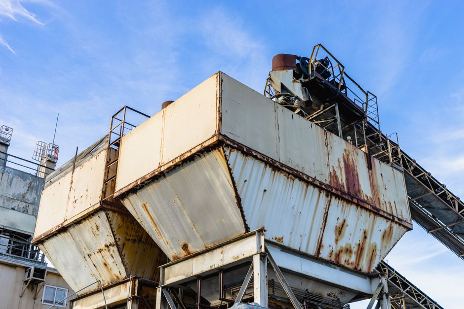 Close-up of rusty industrial equipment against a clear blue sky. (Photo: Robert So / Pexels)