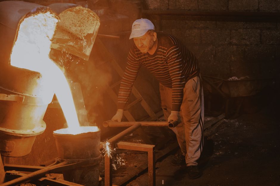 Male worker pours molten metal in a foundry setting, showcasing industrial work. (Photo: Mehmet Turgut  Kirkgoz / Pexels)