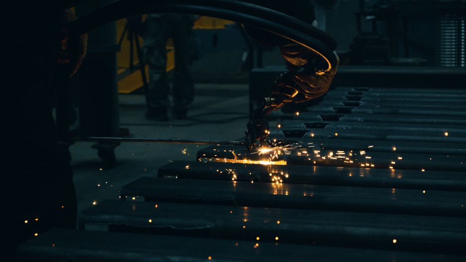 Industrial scene with worker cutting steel, producing dynamic sparks in a factory environment. (Photo: Cemrecan Yurtman / Pexels)