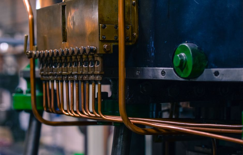 Detailed view of industrial machinery featuring copper tubing and steel components in a factory setting. (Photo: ClickerHappy / Pexels)