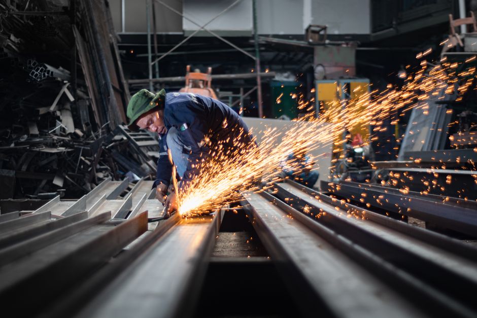A worker uses an angle grinder, creating sparks in a metal workshop. (Photo: ERFIN EKARANA / Pexels)