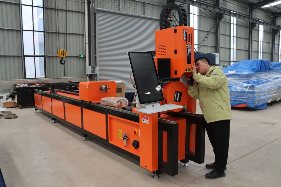 Engineer adjusting an orange CNC machine in a large industrial warehouse setting. (Photo: YIHAI LASER / Pexels)