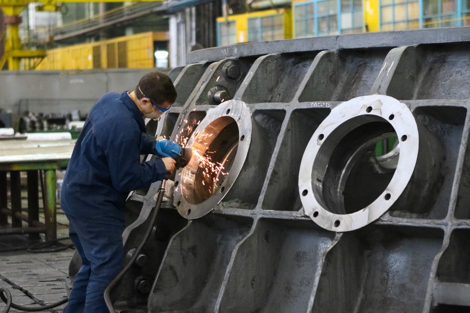 A worker in protective gear grinding metal, creating sparks in a factory setting. (Photo: Kateryna Babaieva / Pexels)